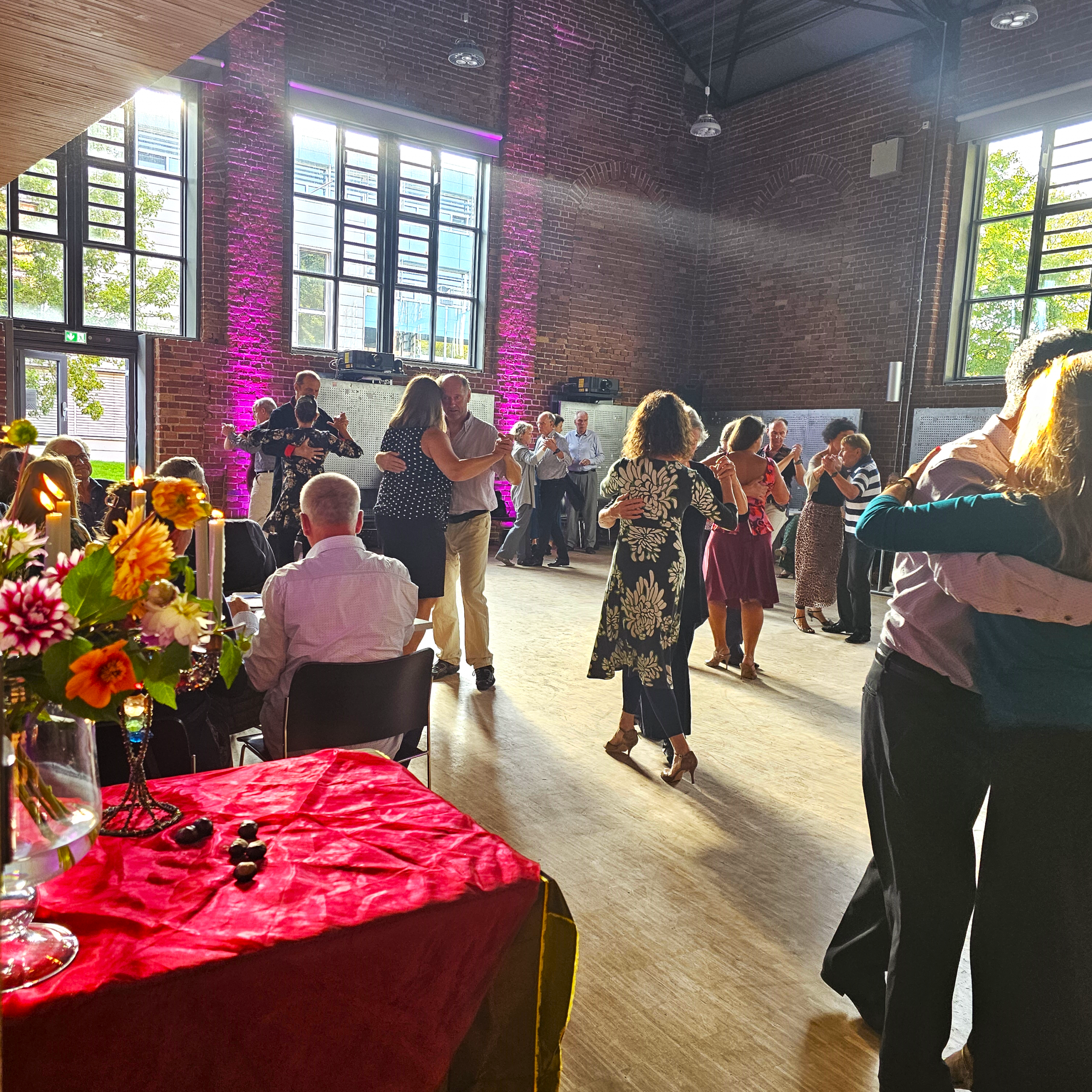 tanzende Paare in einem Hörsaal mit Parkettboden