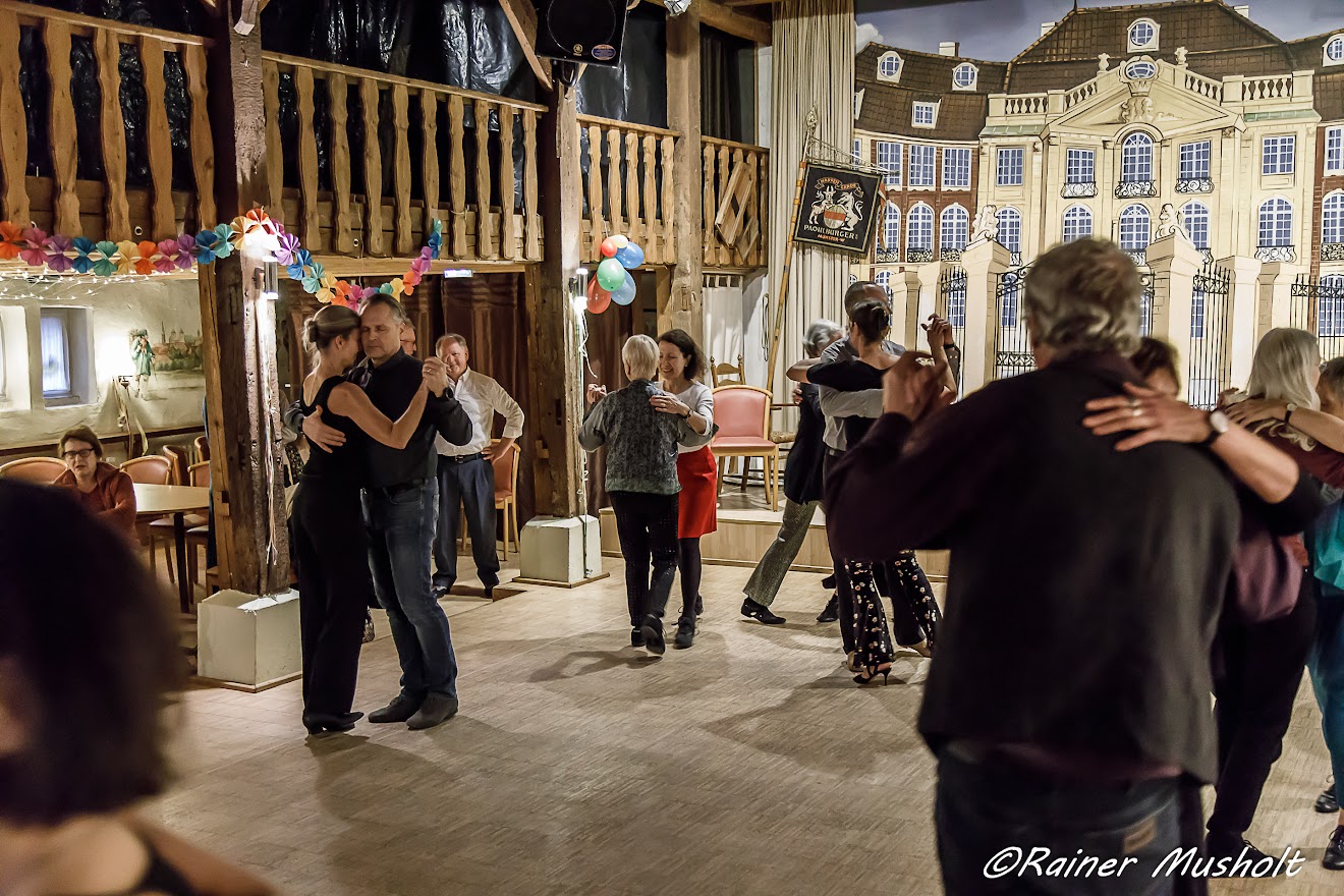 tanzende Paare in einem Hörsaal mit Parkettboden